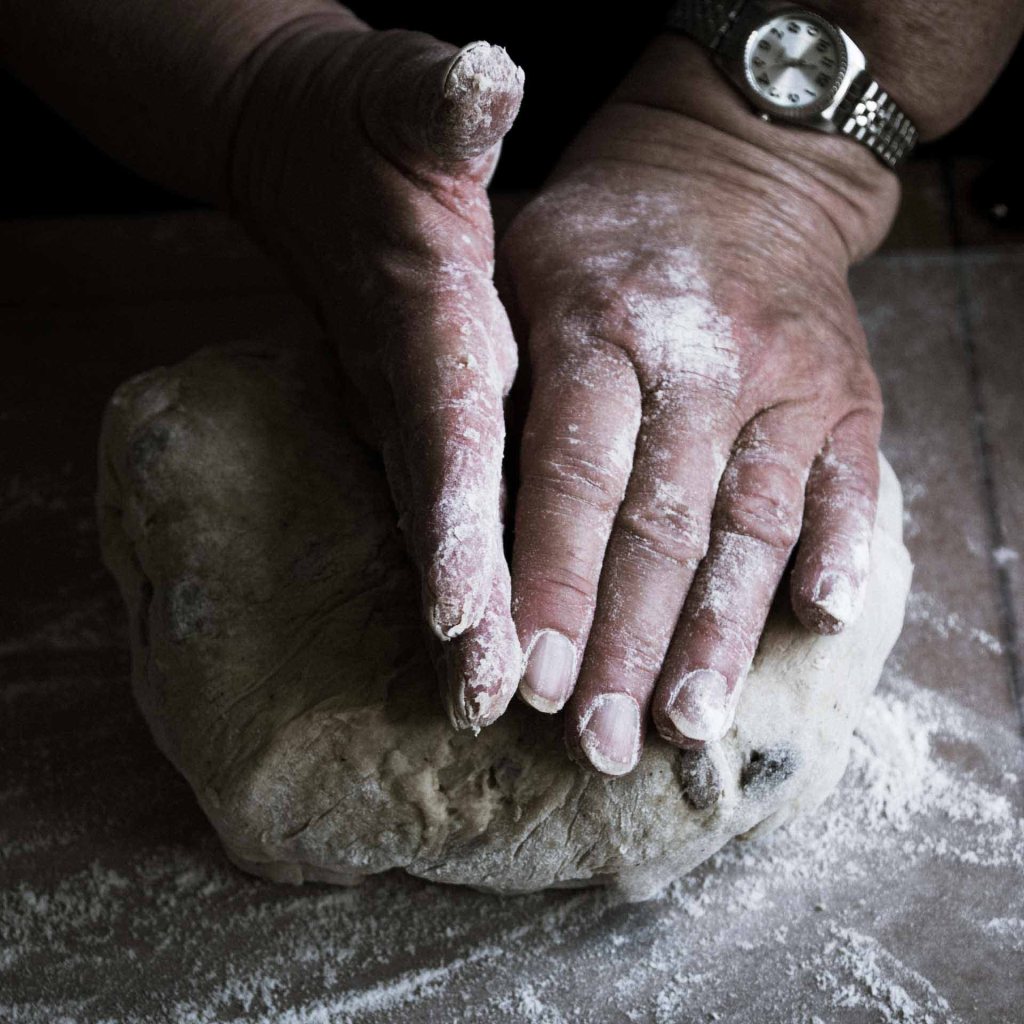 a mother's hands covered in flour making hot cross buns for Good Friday at Easter. 